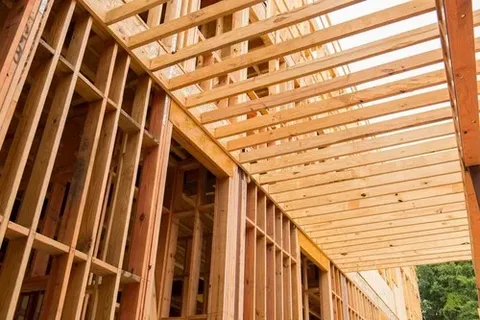 Close-up view of a building under construction, showing the intricate details of newly installed wooden stick framing and roof joists.