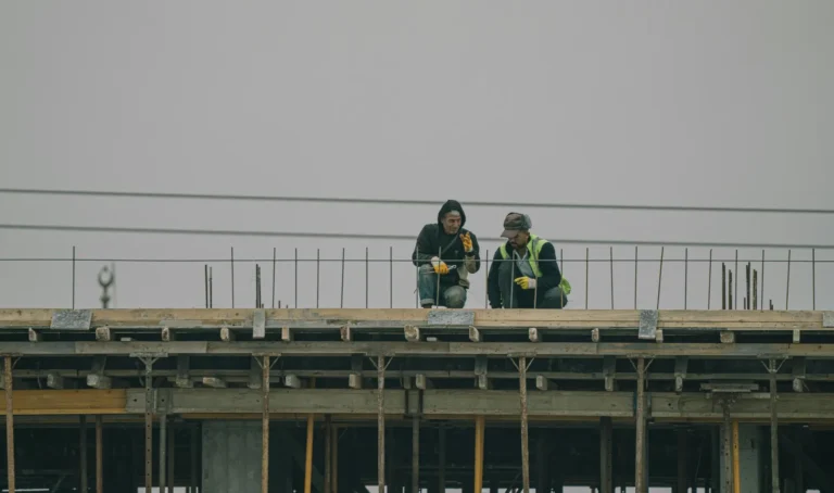 Construction estimating services: two people sitting on a roof of commercial site.
